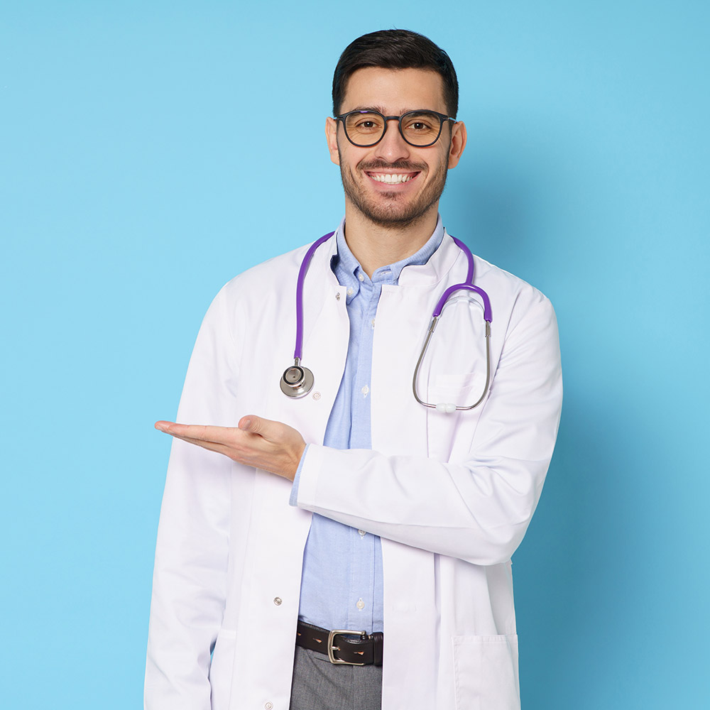 Horizontal banner of smiling young male doctor showing and presenting something with hand, isolated on blue background with copy space on left