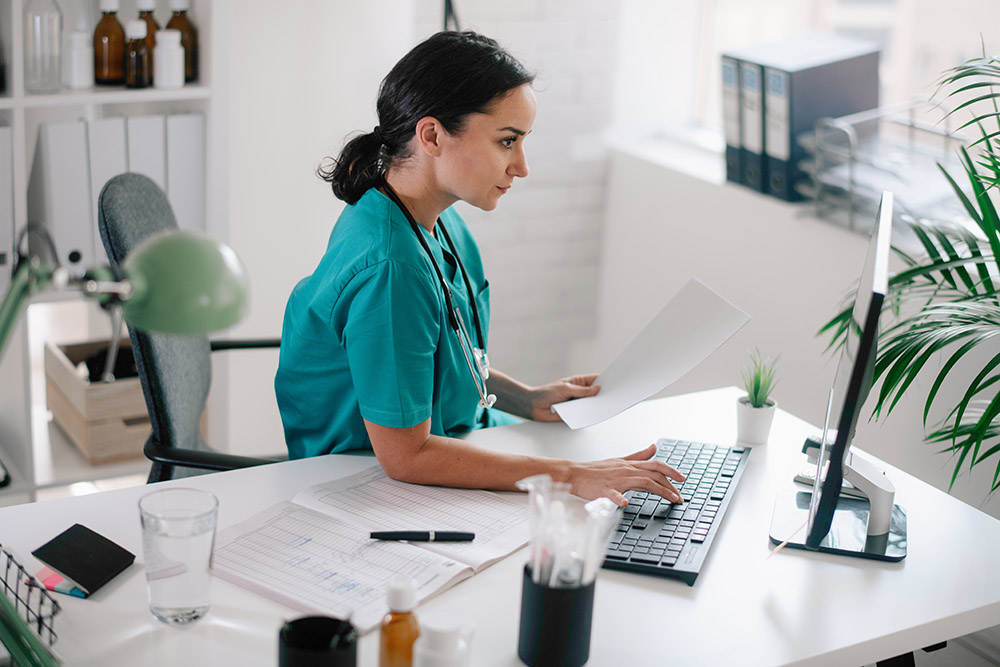 Young beautiful doctor in medical office working on computer