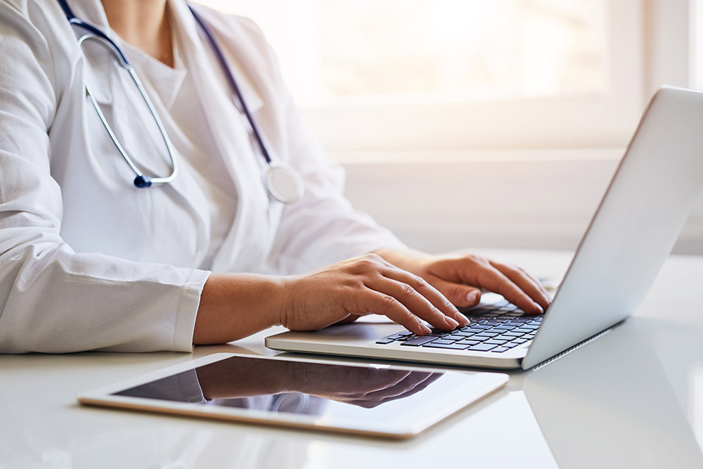 Female doctor typing on her laptop computer in medical office
