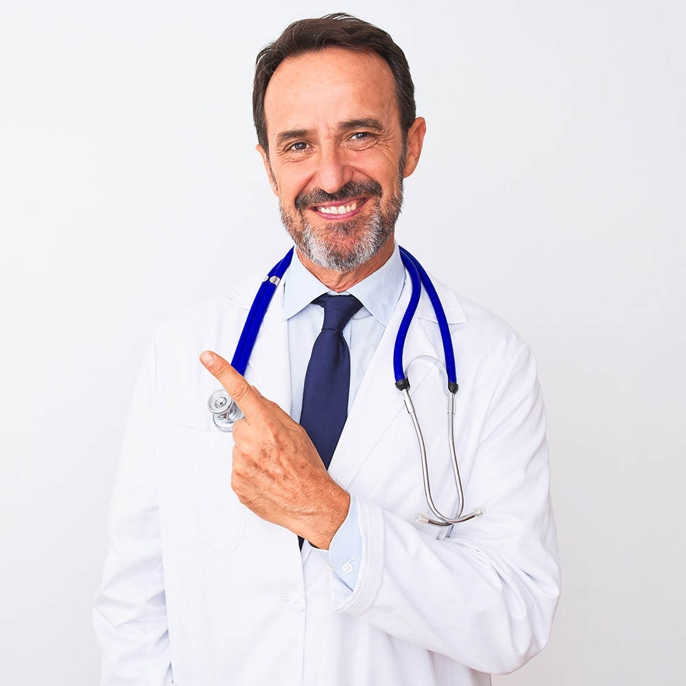 Middle age doctor man wearing coat and stethoscope standing over isolated white background cheerful with a smile of face pointing with hand and finger up to the side with happy and natural expression on face