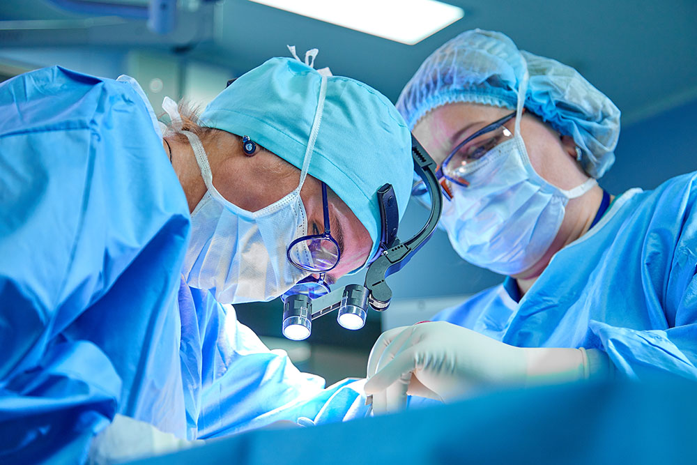 A surgeon's team in uniform performs an operation on a patient at a cardiac surgery clinic.